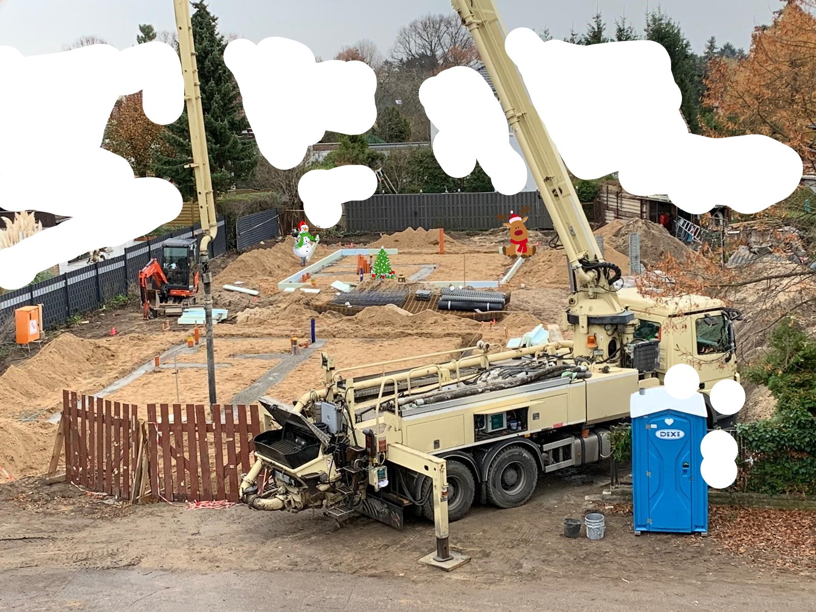 Große Baustelle mit Kran, Baggern, Sandhügeln und einer mobilen Toilette im Vordergrund