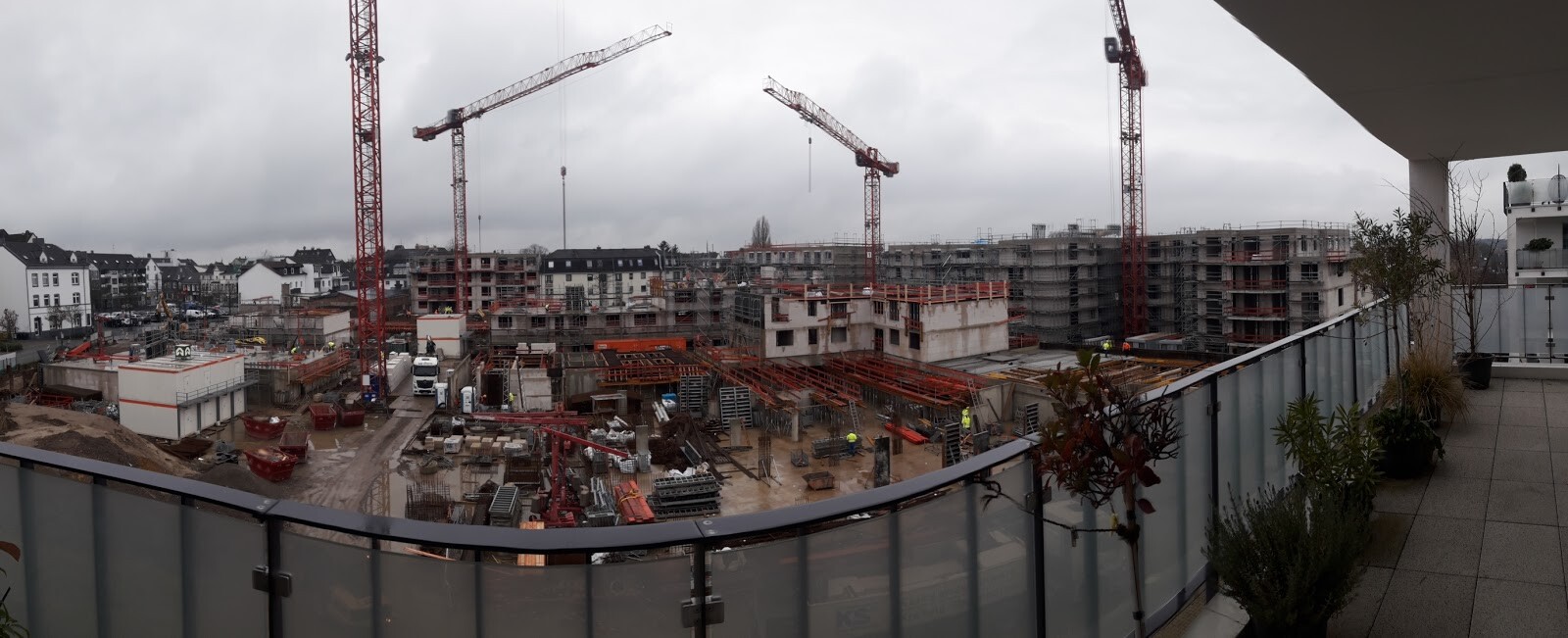 Panoramablick von Balkon auf Großbaustelle mit Kränen, Gerüsten und halbfertigen Gebäuden