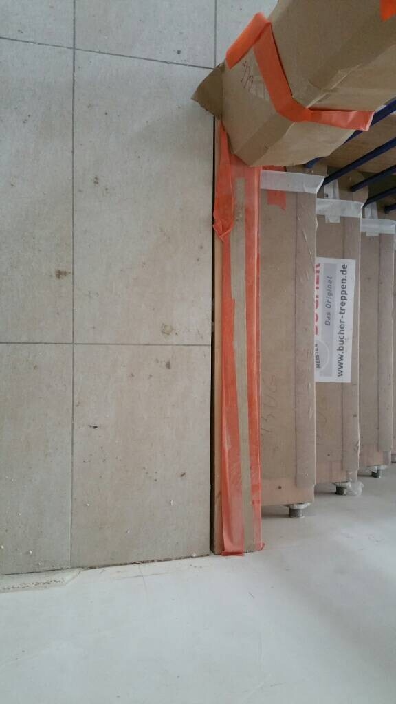 Grosse beige Bodenfliesen stehen an einer Baustelle, verpackt mit orangefarbener Schutzfolie