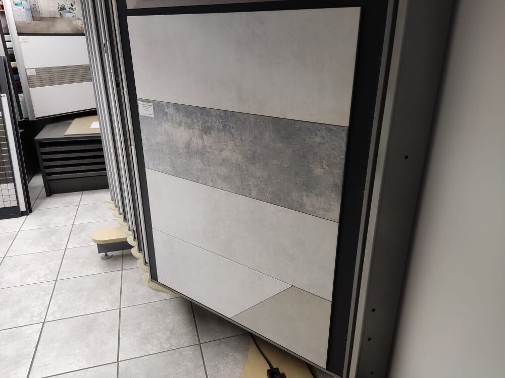 Ausstellung von Bodenfliesen-Proben in einem Fliesenstudio mit beige- und grautönen Mustern.