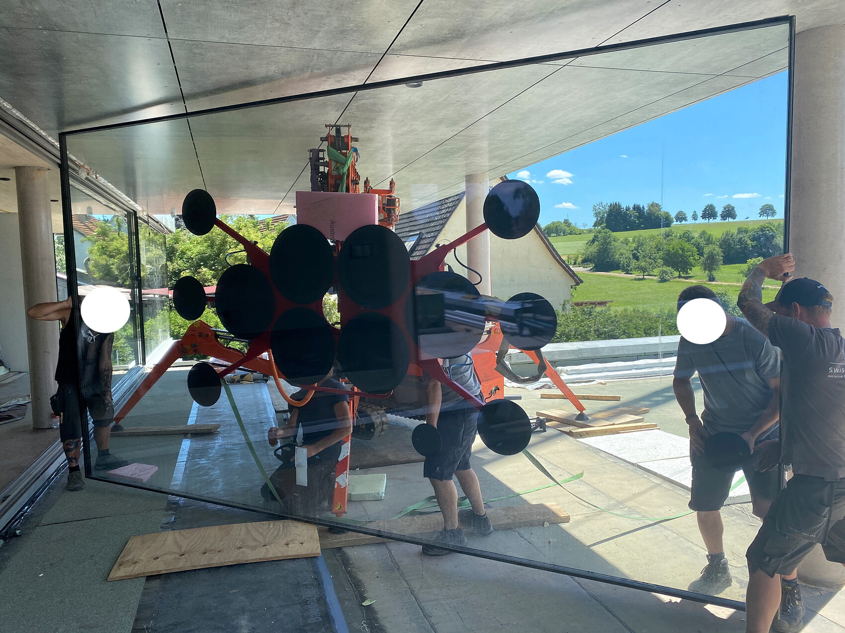 Große rote Skulptur mit schwarzen Kreisen wird von Arbeitern montiert, Glaswand dahinter.