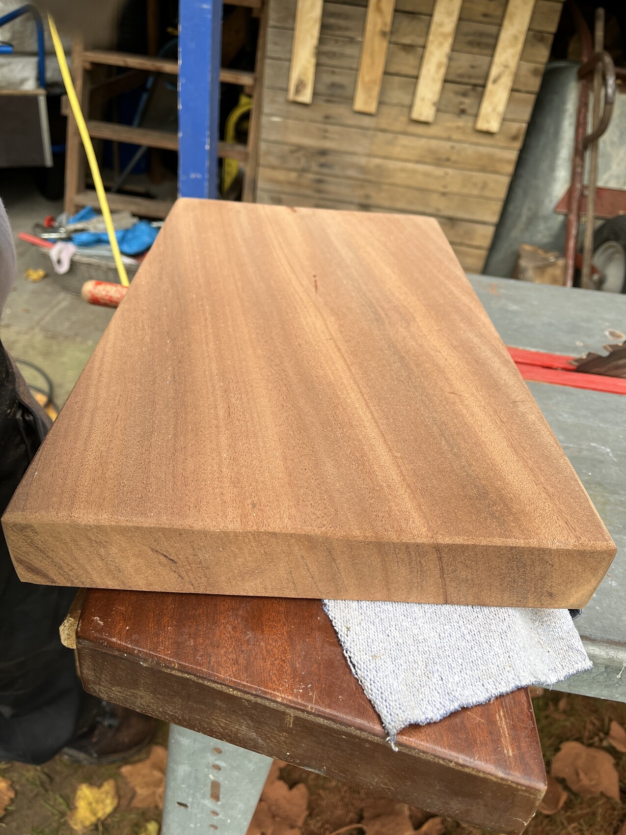 Große helle Holzplatte liegt auf dunklerem Brett in einer Werkstatt.
