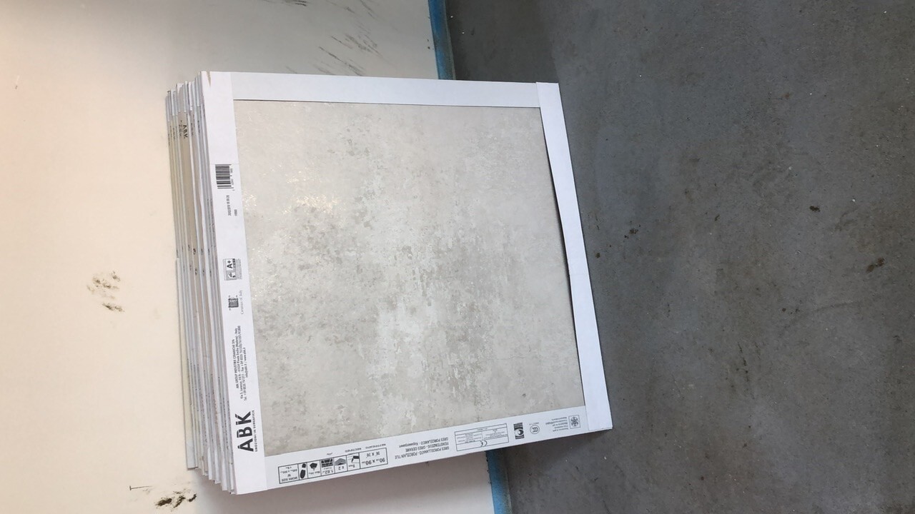 Graue Fliesenplatten stapeln sich gegen eine Wand in der Werkstatt.