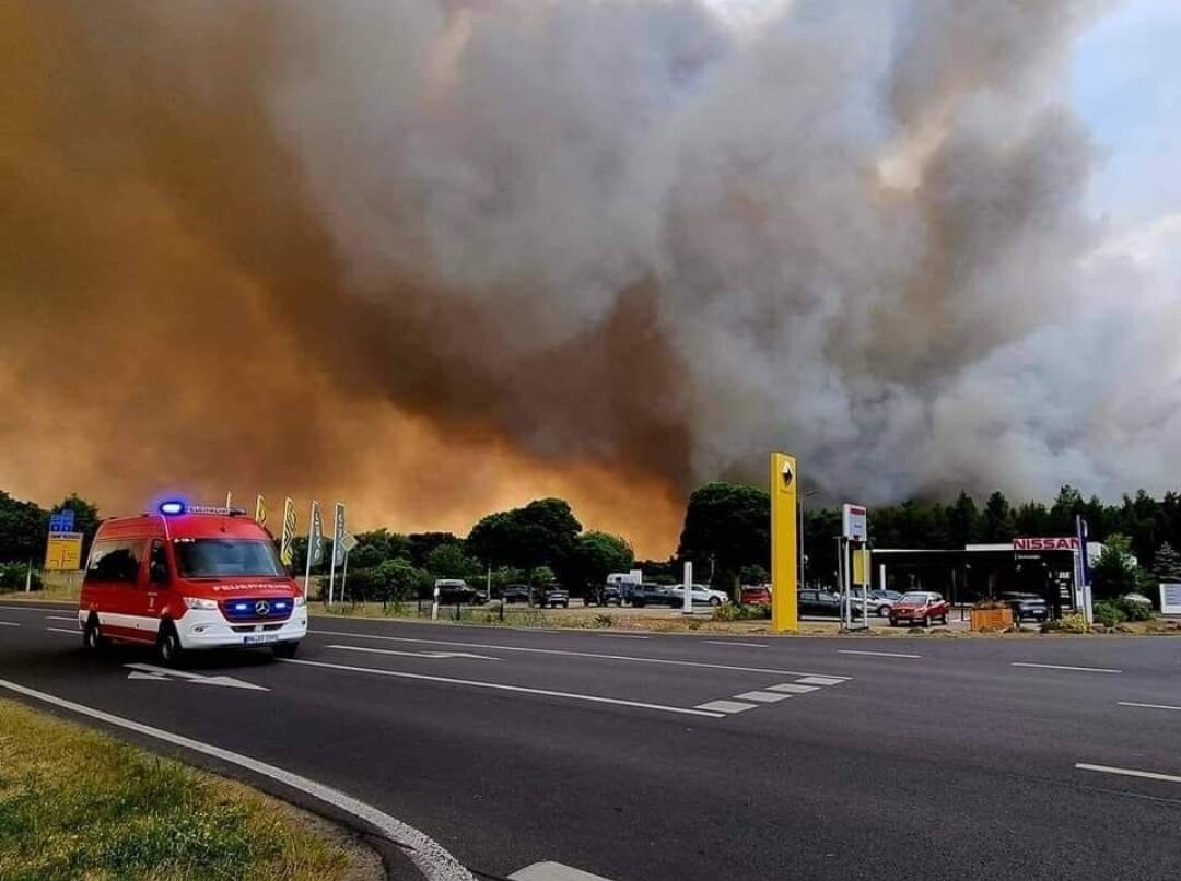 Großer Waldbrand am Straßenrand mit dichter Rauchwolke; Rettungswagen mit Blaulicht auf Autobahn