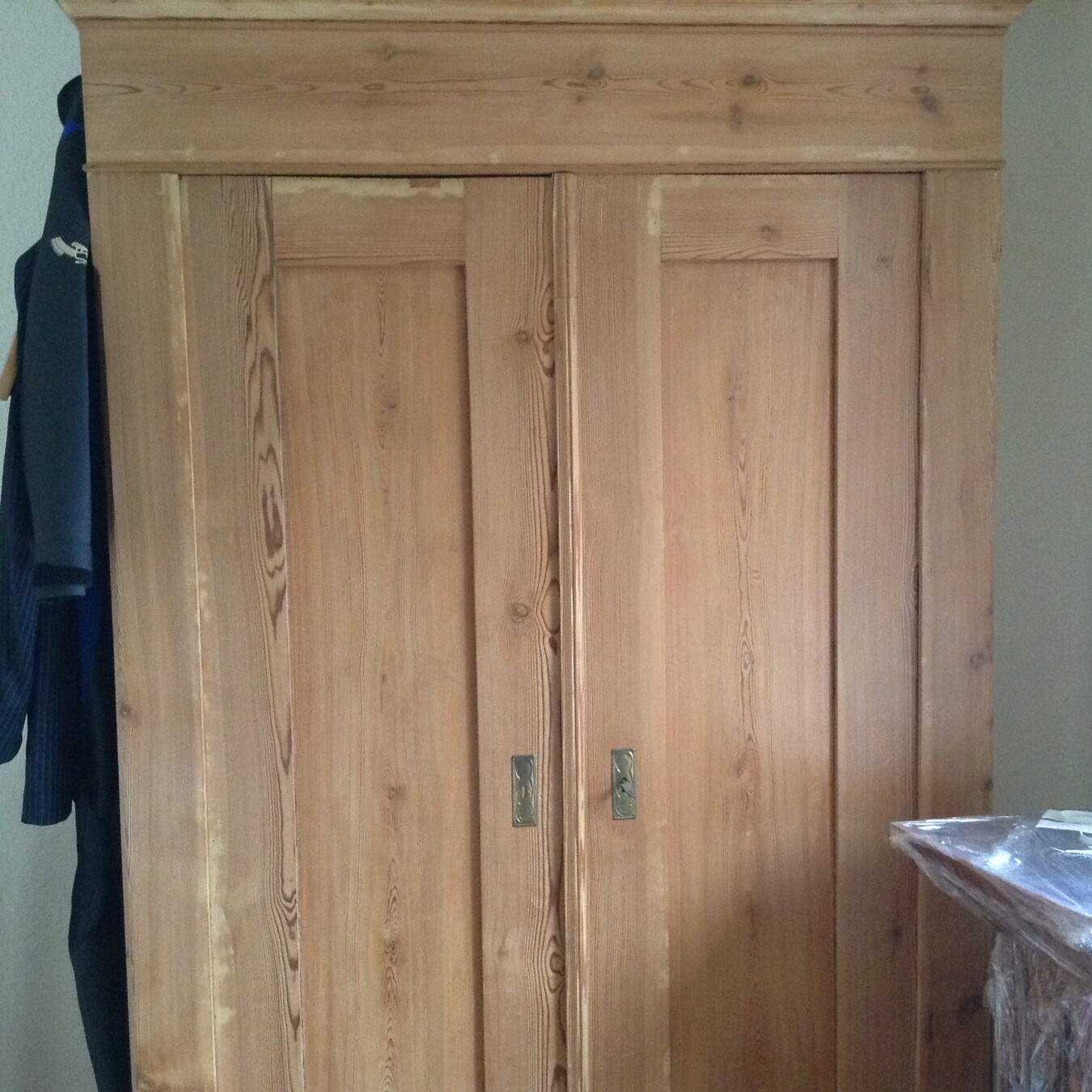 Großer Holzkasten-Schrank mit zwei Türen steht in einem Zimmer.