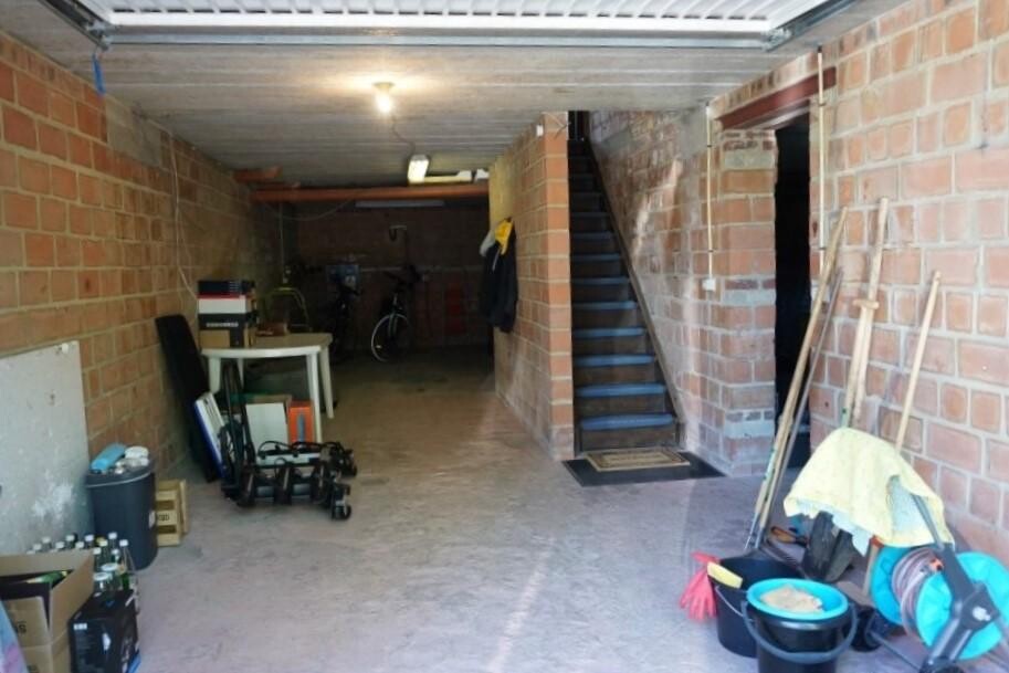 Unterkellerte Garage mit Treppe; Kartons, Werkzeuge, Fahrrad und Reinigungsbedarf.