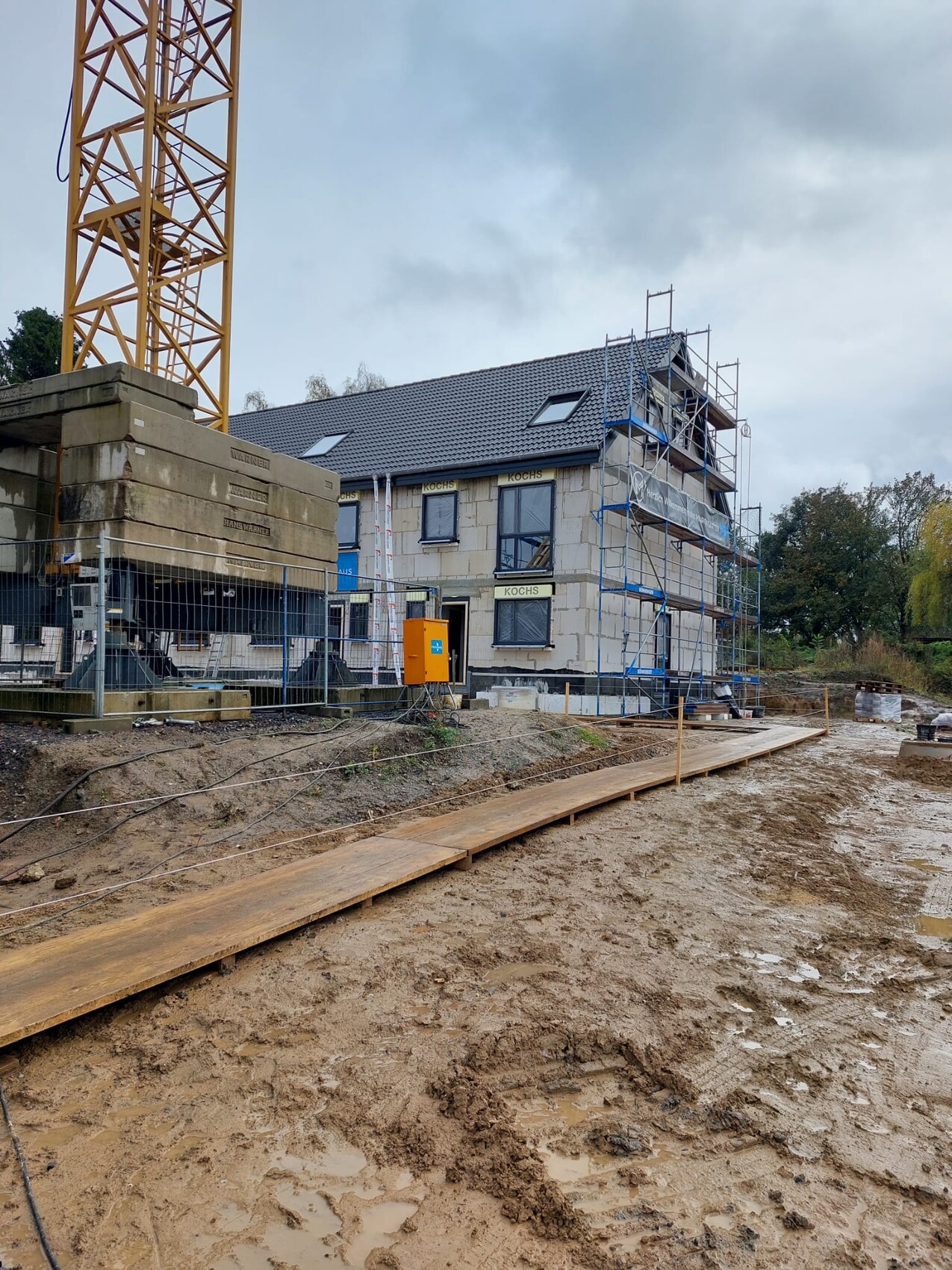Baustelle mit Rohbau, Kran, Gerüst und Bauplatz am Neubau des Hauses
