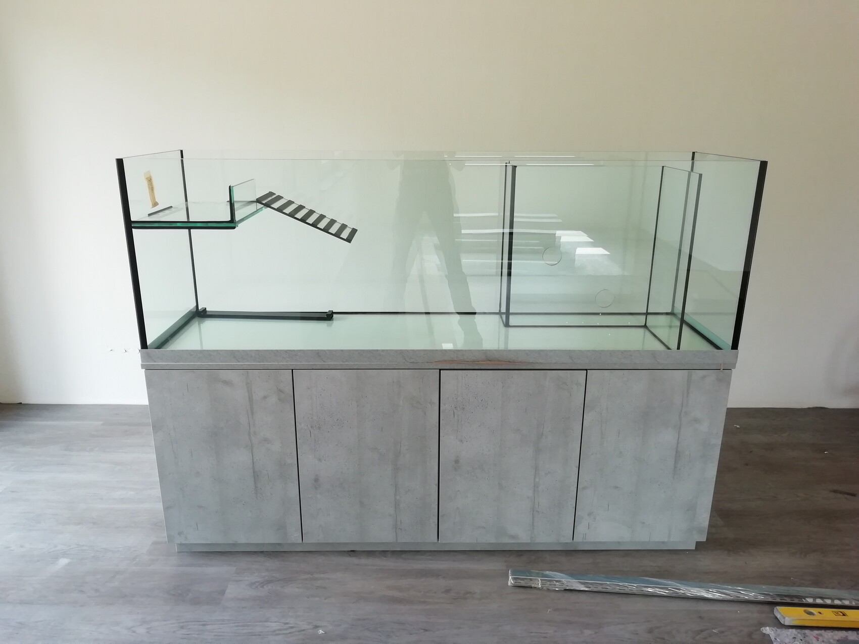 Große Glasvitrine auf grauem Betonunterschrank; linke Rampenstrecke, rechte Glasabschnitte.