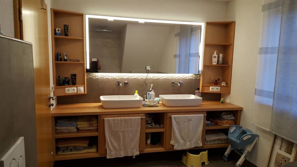 Badezimmer mit Doppelwaschbecken, großem Spiegel, Holzmöbeln und Handtüchern