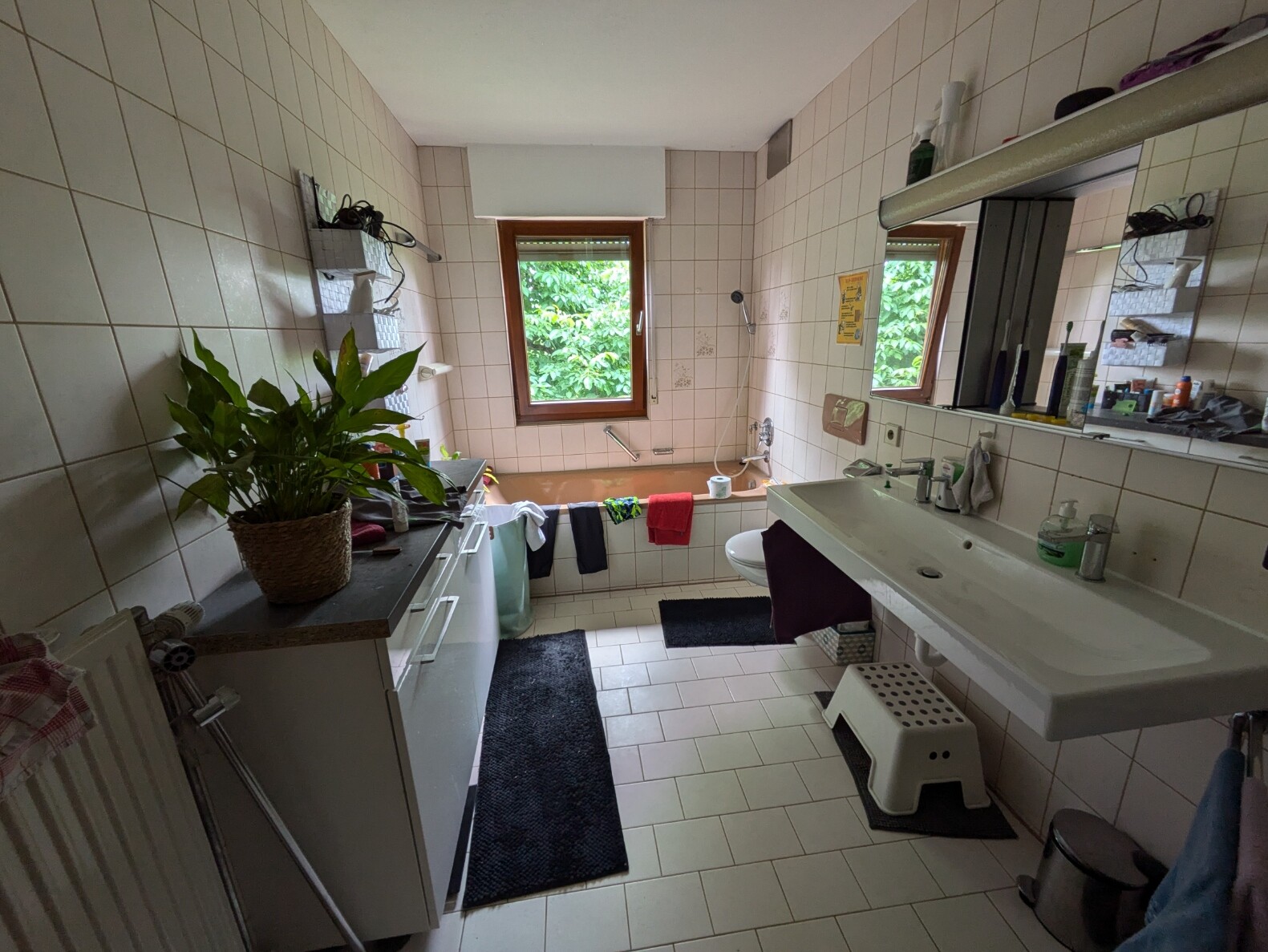Badezimmer mit Waschbecken, Badewanne, Fliesen, Fenster und Spiegel