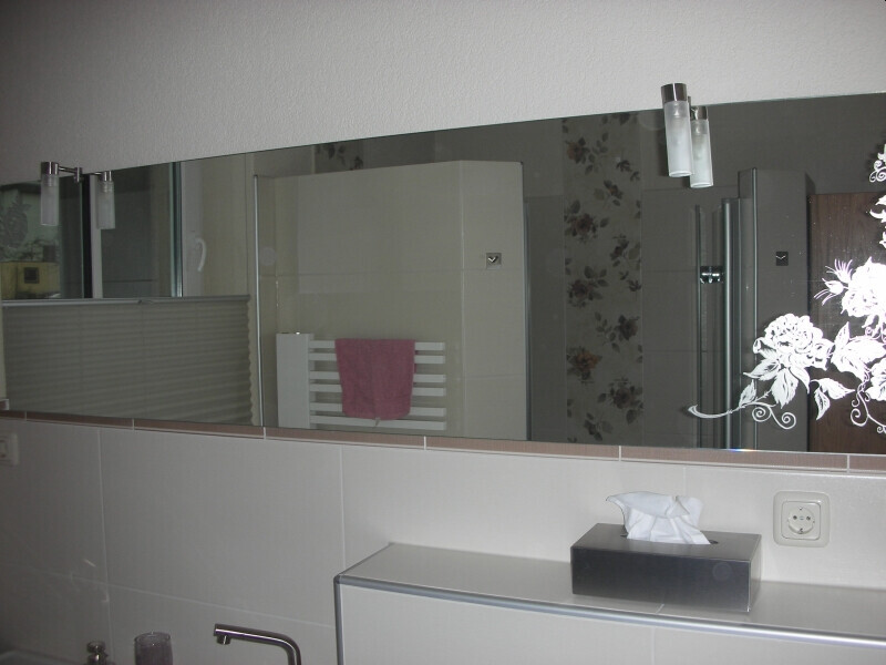 Badezimmer mit großer Spiegelwand, pinkem Handtuch am Heizkörper, Waschtisch mit Taschentuchbox.