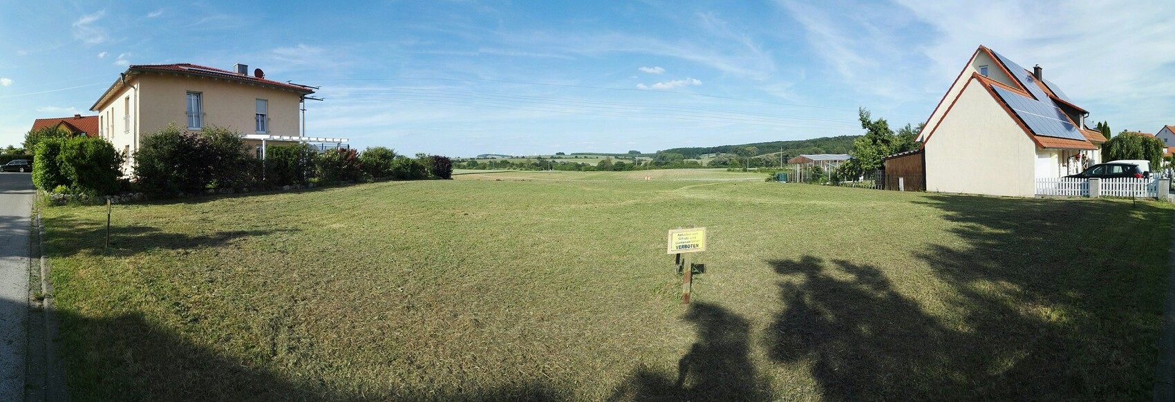 Panorama eines offenen Baugrundstücks zwischen zwei Häusern mit Gartenfläche