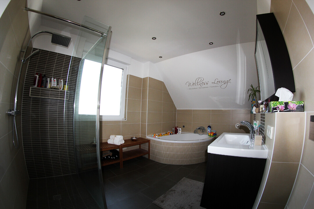 Modernes Bad mit begehbarer Dusche, Eckbadewanne, Waschbecken und Wellness Lounge.