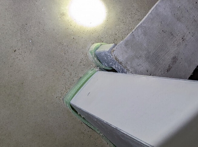 Nahaufnahme einer grauen Treppenstufe mit grünem Gummi-Schutzrand an Beton.