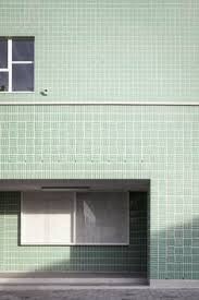 Außenfassade eines Gebäudes mit grünen Fliesen, Fenster und Eingangstür
