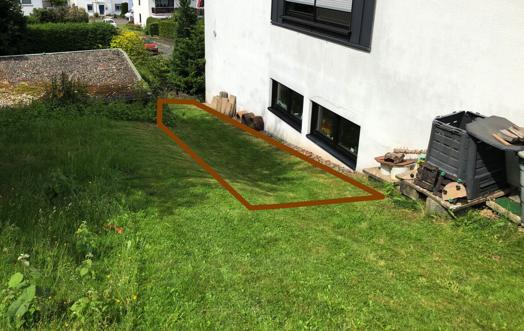 Gartenhang neben weißem Haus; braun markierte Fläche zeigt eine grasbewachsene Zone.
