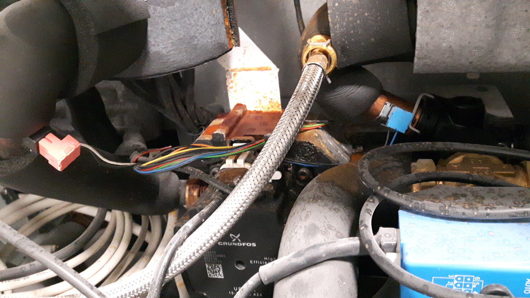 Innenansicht eines technischen Geräts mit Kabeln, Schläuchen und Grundfos-Komponente
