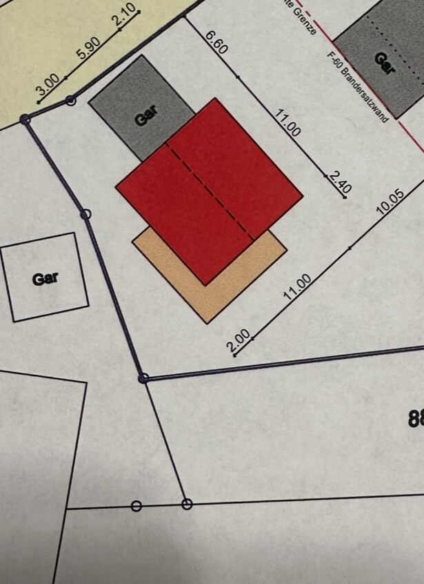 Grundrissplan mit rotem Haus, grauer Garage und Parzellenabgrenzung mit Maßlinien