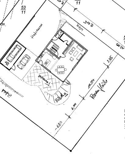 Grundriss eines Hauses mit Garage, zwei Pkw-Stellplätzen, Wohnzimmer, Küche, Bad.