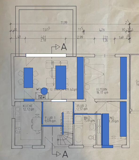 Grundriss eines Hauses mit Räumen wie Küche, Wohnen, Flur und Eltern, blau markierte Bauteile.