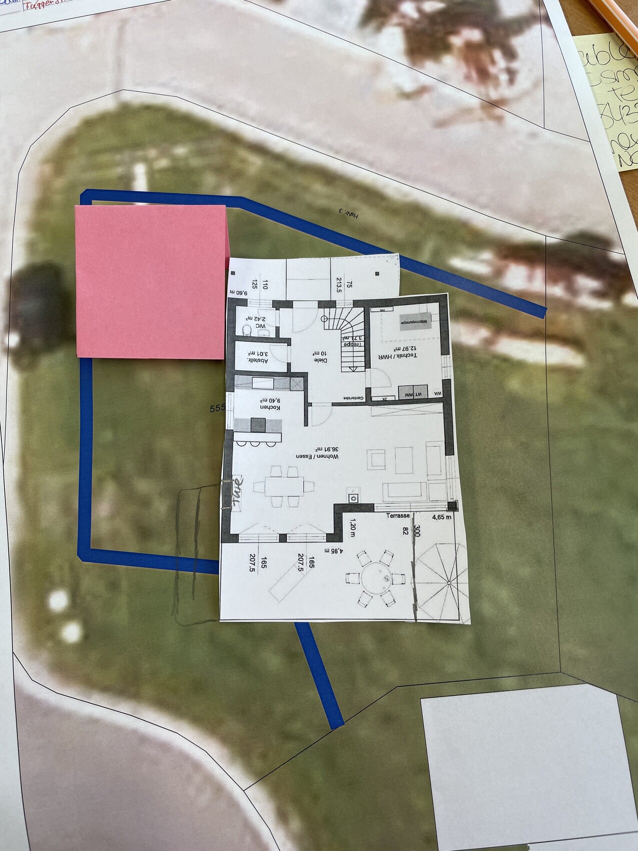 Überlagerter Haus-Grundriss auf Geländeplan mit blauem Rand; pinkes Blockmodell links.