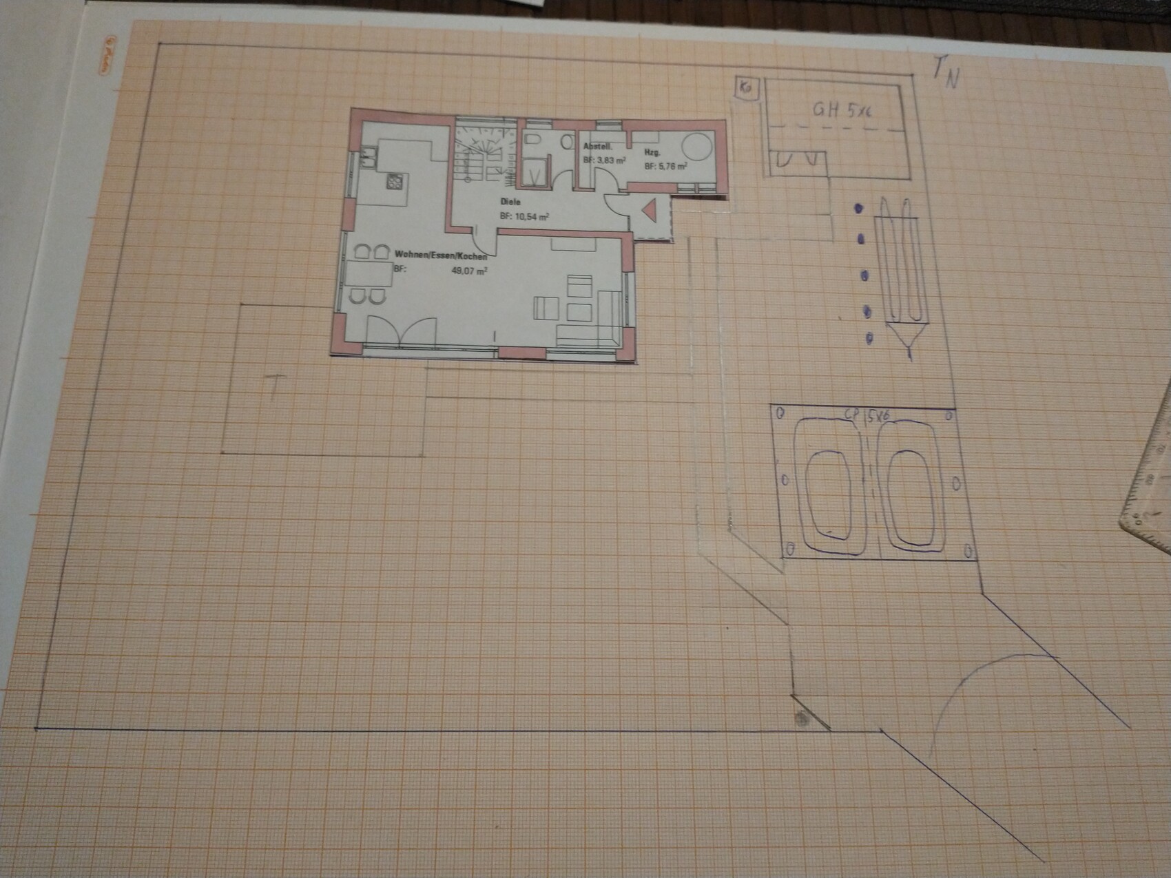 Grundriss eines Hauses mit Wohnzimmer, Küche, Diele und Bad, gezeichnet auf Papier.