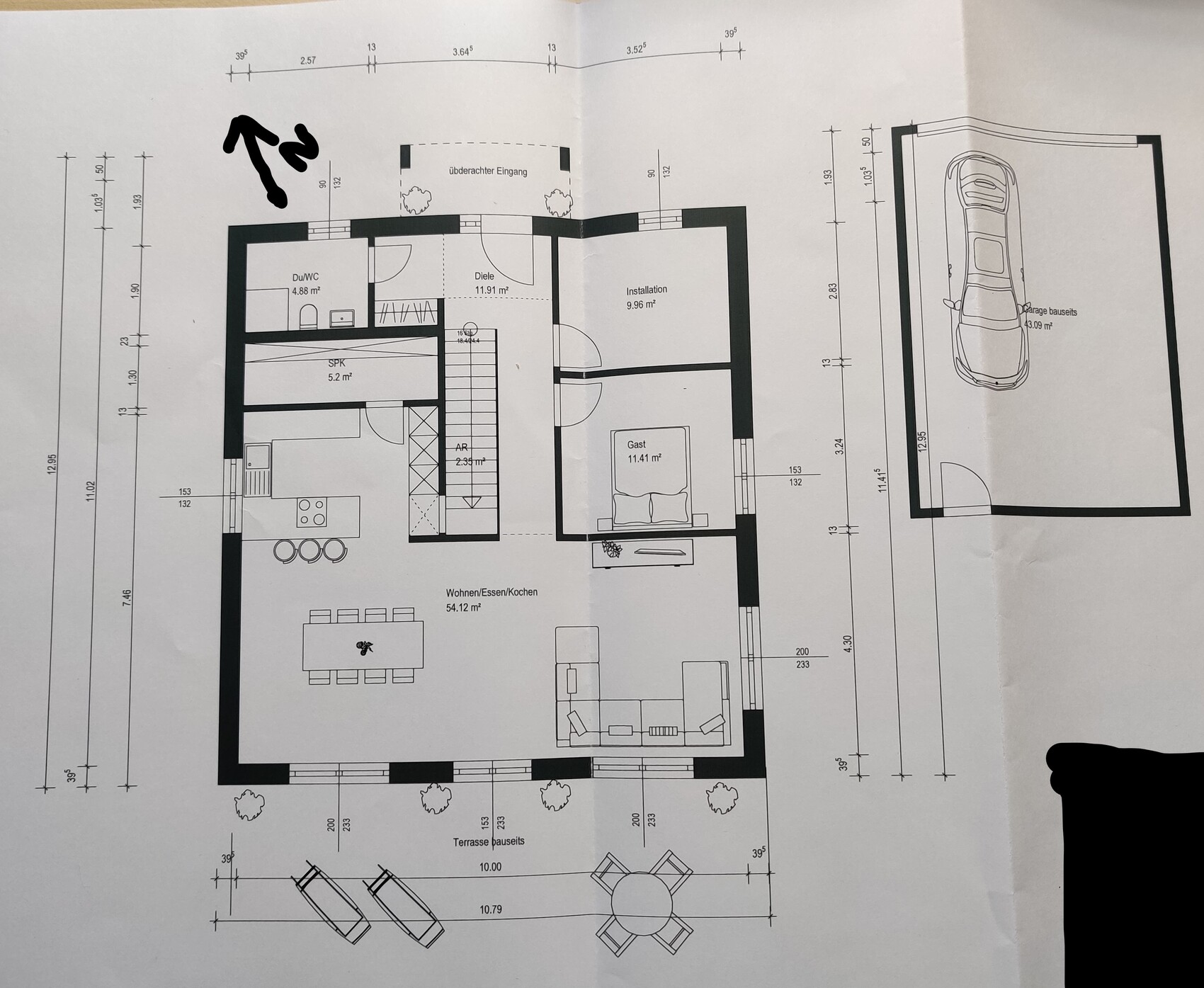 Grundriss eines Hauses: Wohnzimmer, Küche, Essbereich, Diele, Bad, Gästezimmer, Garage, Terrasse.