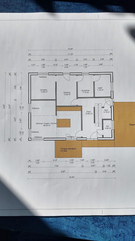 Grundriss eines Hauses: Wohnen/Essen/Kochen, Schlafen, Ankleide, Duschbad, Diele, Terrasse, Carport.