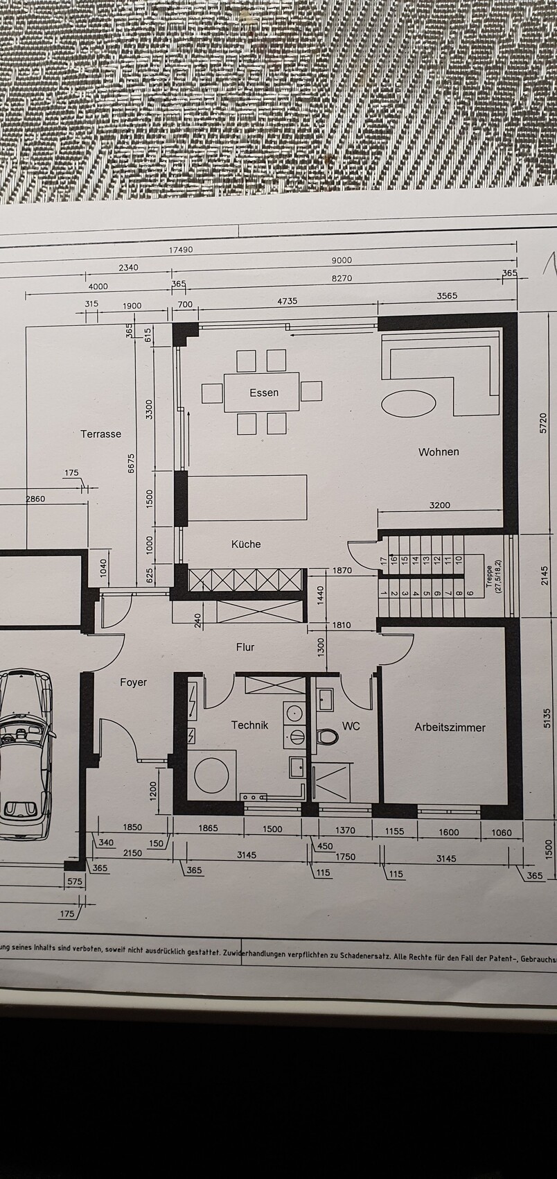 Grundriss eines Hauses mit Terrasse, Küche, Essen, Wohnen, Arbeitszimmer, Flur, WC und Treppe.
