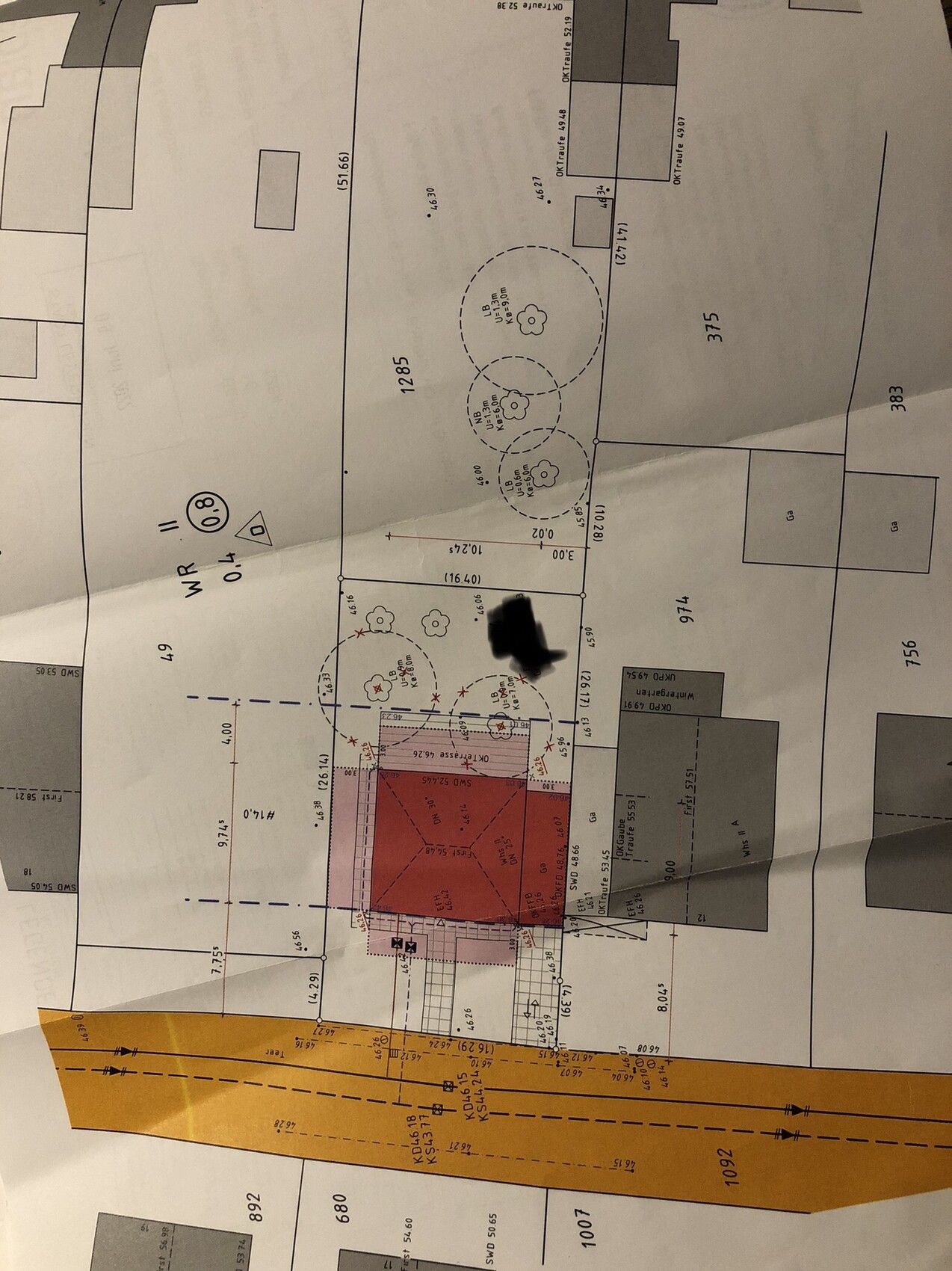 Lageplan: rotes Gebäuderechteck, blaue Setback-Linien, Bäume, angrenzende Straßen.