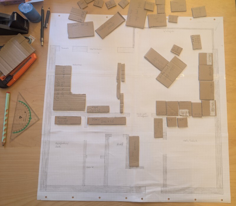 Grundrissplan auf Papier mit Kartonbausteinen und Zeichenwerkzeugen auf einer Arbeitsfläche