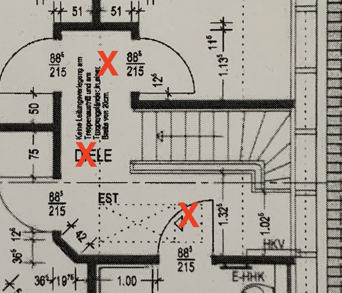Grundriss eines Gebäudeteils mit Treppen und Wänden; drei rote X markieren Flächen.