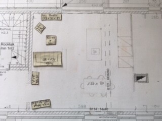 Grundrisszeichnung eines Innenraums mit Möbeln (Sofa, Tische) und Türen.