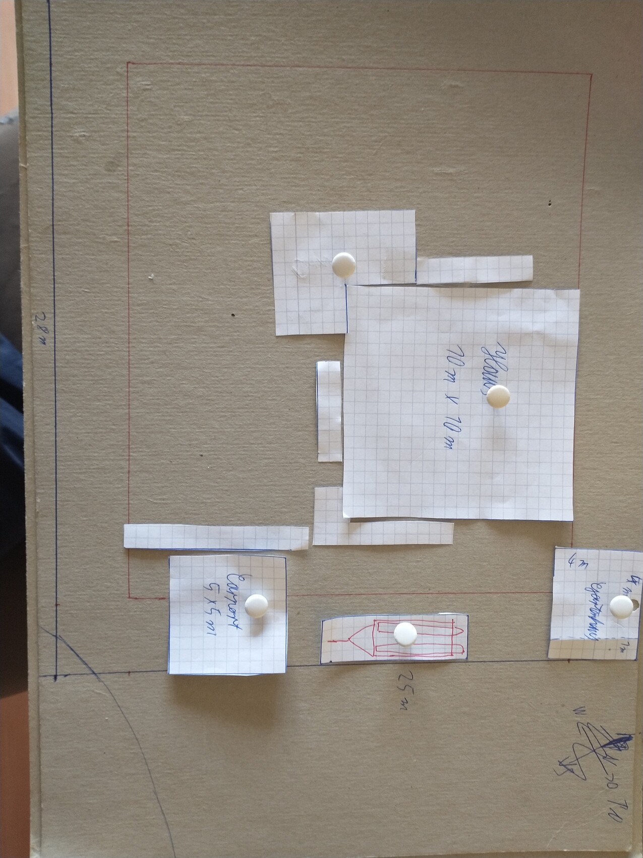 Kartonboden mit zugeschnittenen Papierquadraten zur Grundrissplanung eines Hauses