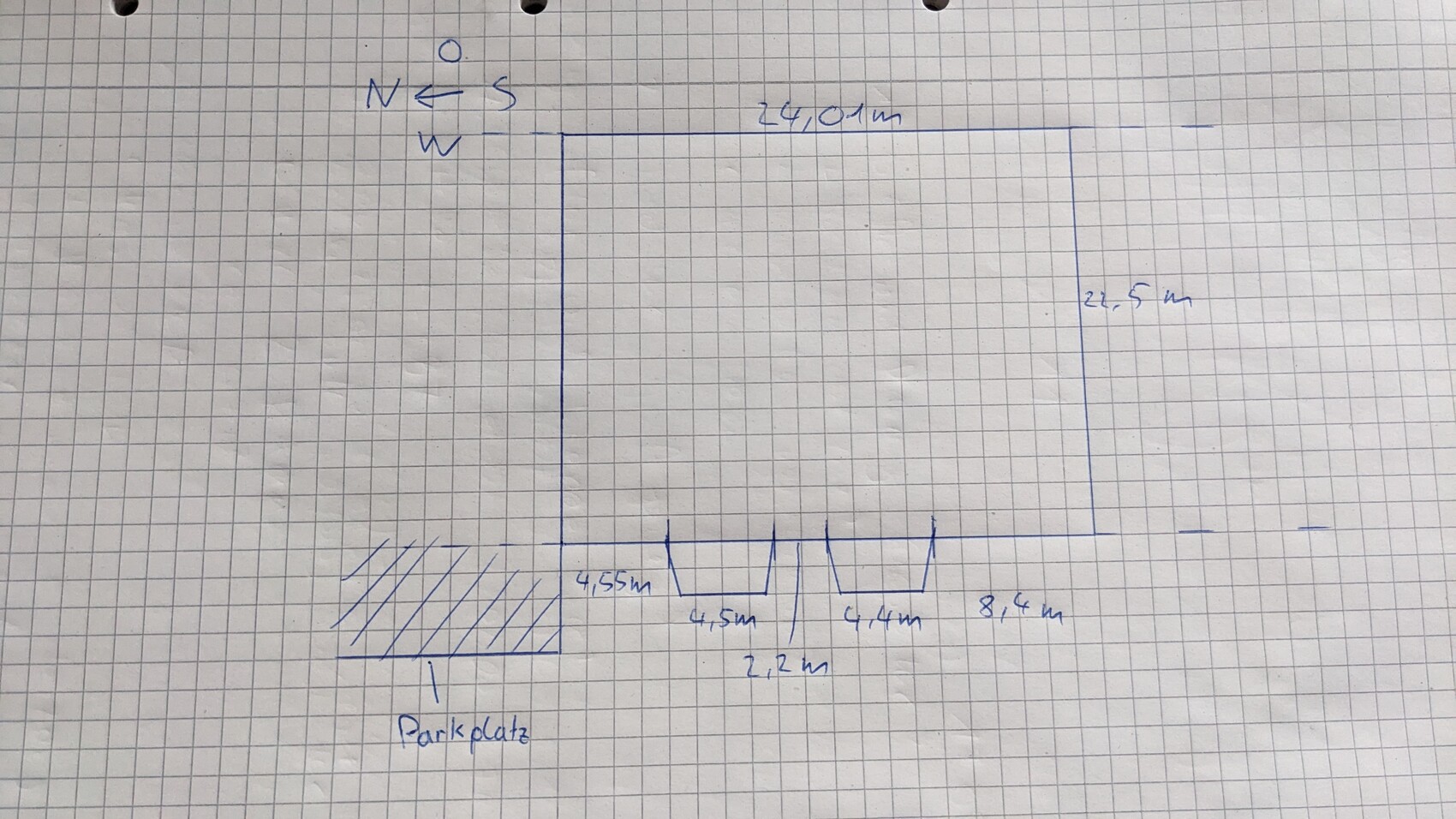 Handgezeichnete 2D-Grundrissskizze eines Gebäudes mit Parkplätzen auf kariertem Papier.