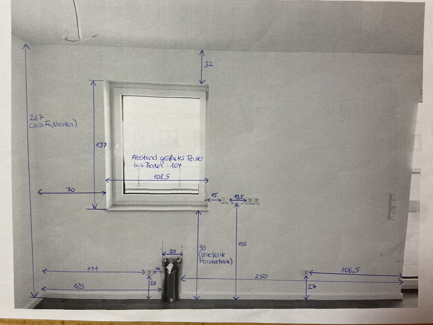 Foto einer Wand mit Fenster und vielen Maßangaben in blauem Marker