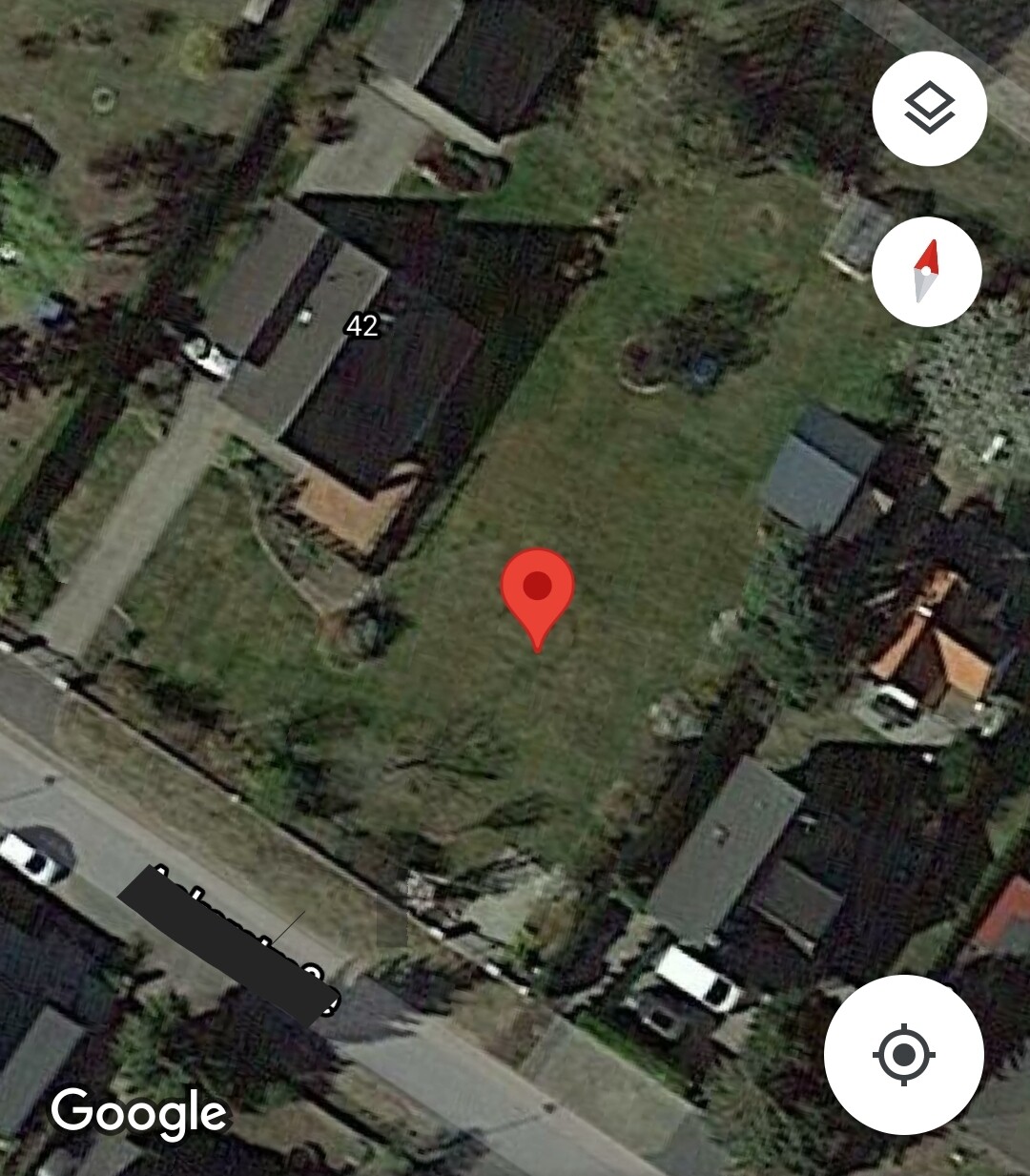 Satellitenaufnahme eines Wohnviertels mit grünem Garten und rotem Standort-Pin.