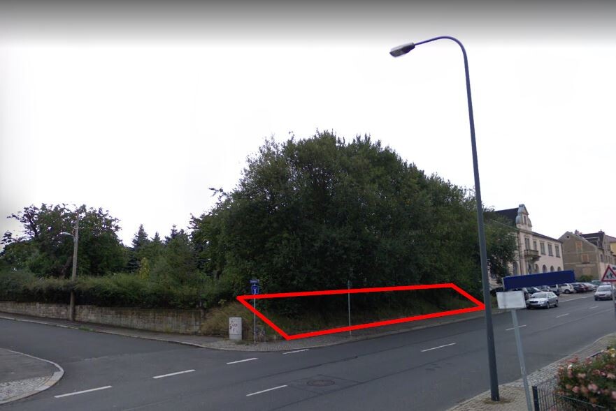 Straße mit roter Umrandung markiert Grundstücksgrenze neben Bäumen und Gebäuden
