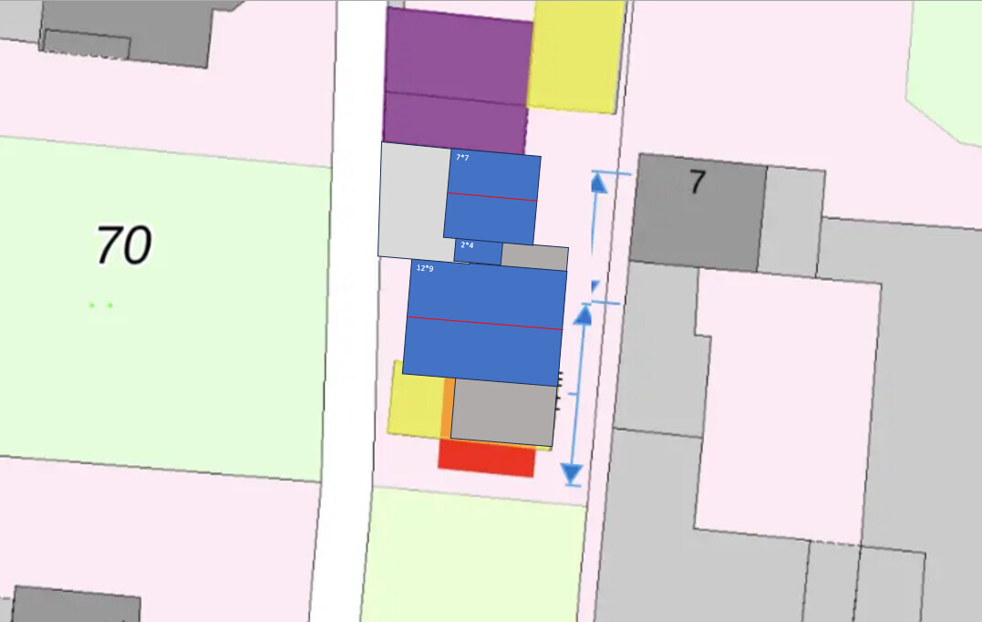 Lageplan: Blaue Gebäudeblöcke neben einer vertikalen Straße, rote Maßlinien.