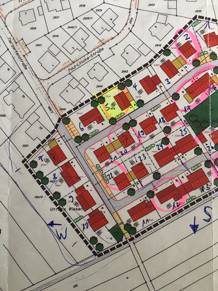 Lageplan eines Wohnviertels mit roten Häusern, Bäumen, Straßen und Markierungen.