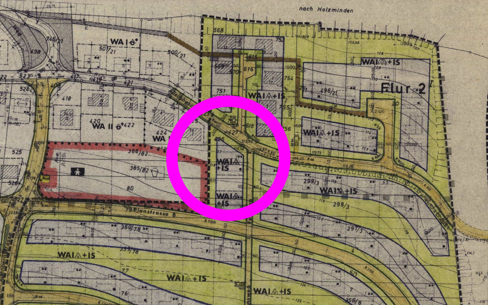 Bebauungsplan mit farbigen Zonen; der Kreis markiert eine zentrale Straßenkreuzung mit Gebäuden.