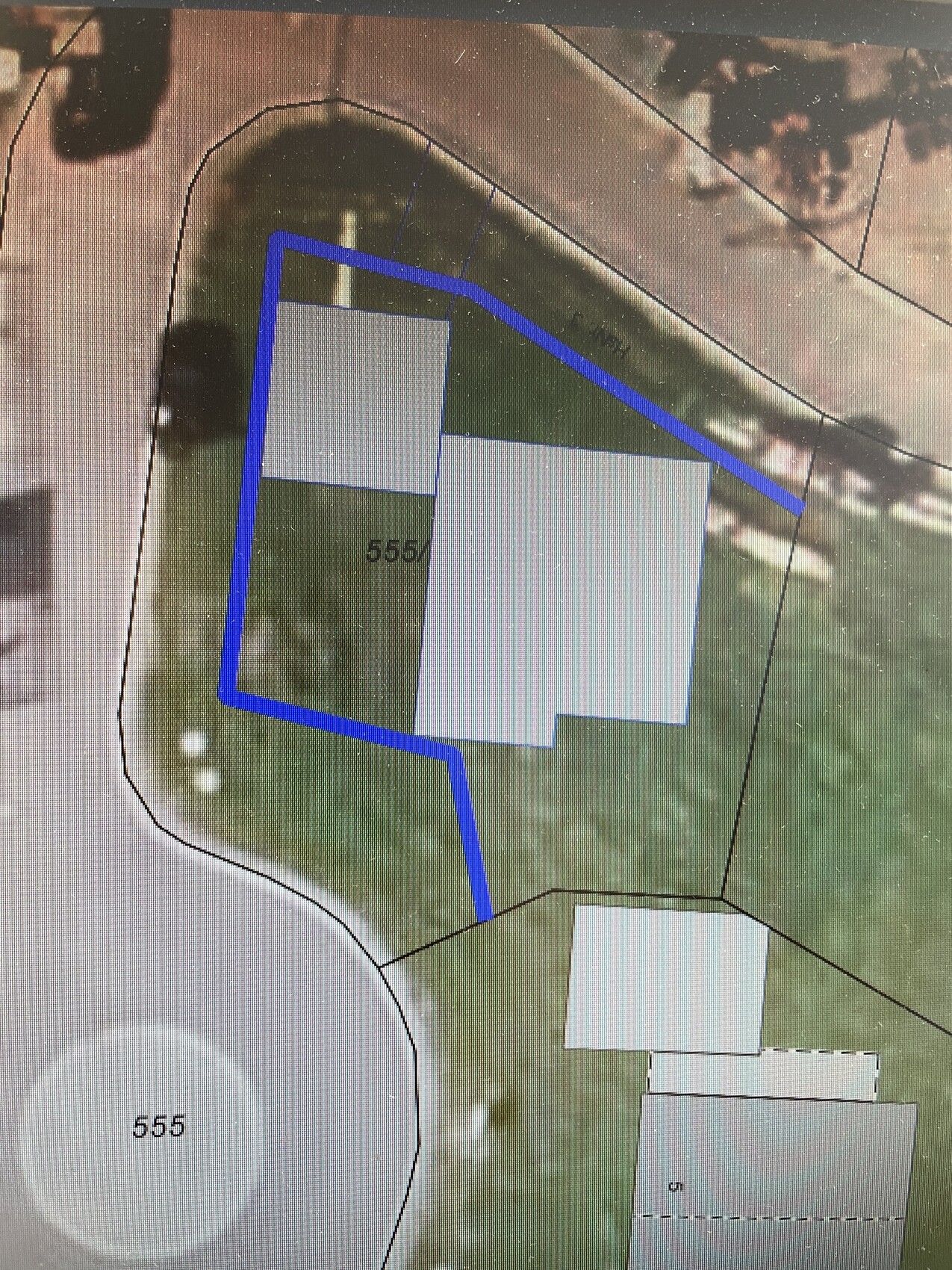 Lageplan eines Grundstücks: blaue Umrandung um zwei Gebäude auf Grünfläche.