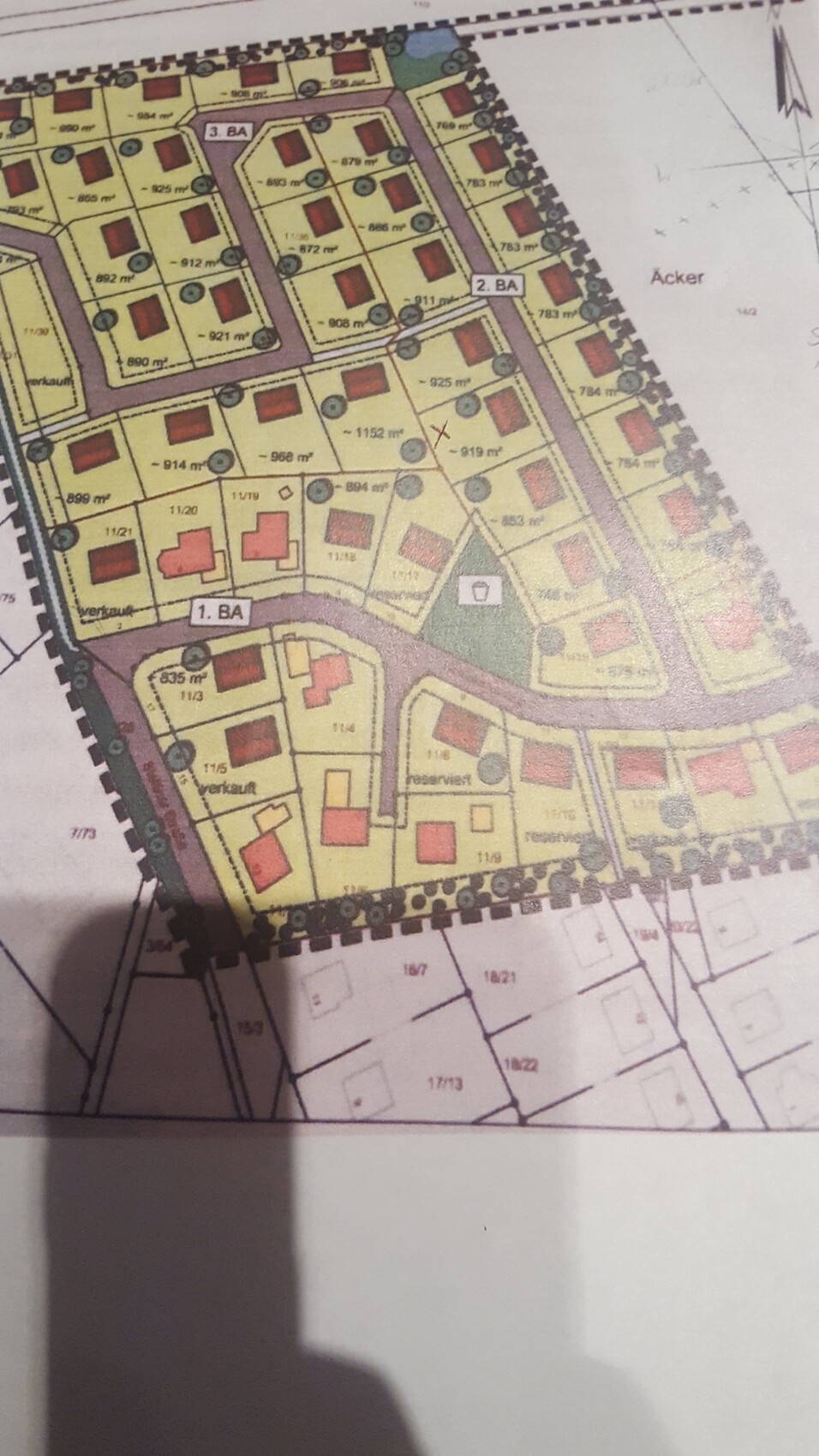 Lageplan eines Baugebiets mit gelben Grundstücken, roten Gebäuden und Straßennetzen