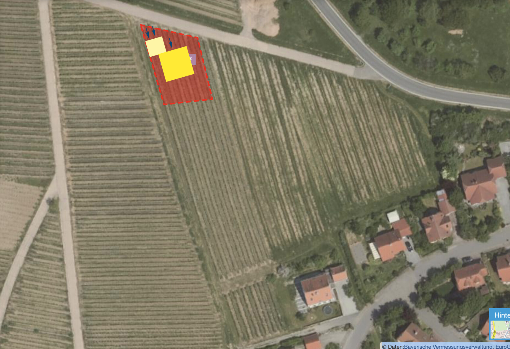 Luftbild eines markierten Baugrundstücks im Feldgebiet neben Wohnhäusern.