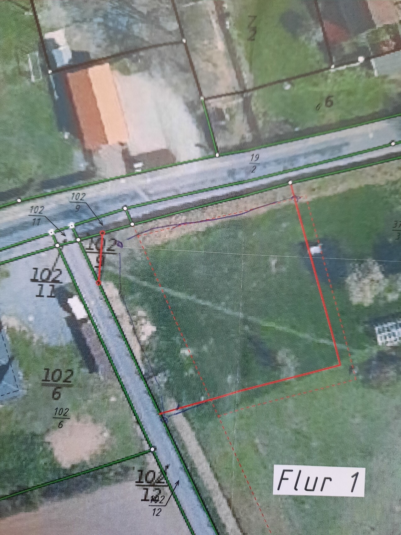 Lageplan: Grüne Parzellenlinien, rotes Grenzpolygon und Straßenverlauf sichtbar.