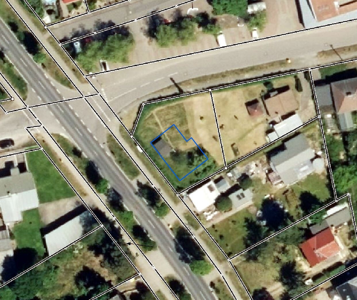 Luftaufnahme eines Baugrundstücks mit Grenzen und blau markiertem Bauplatz neben einer Straße.