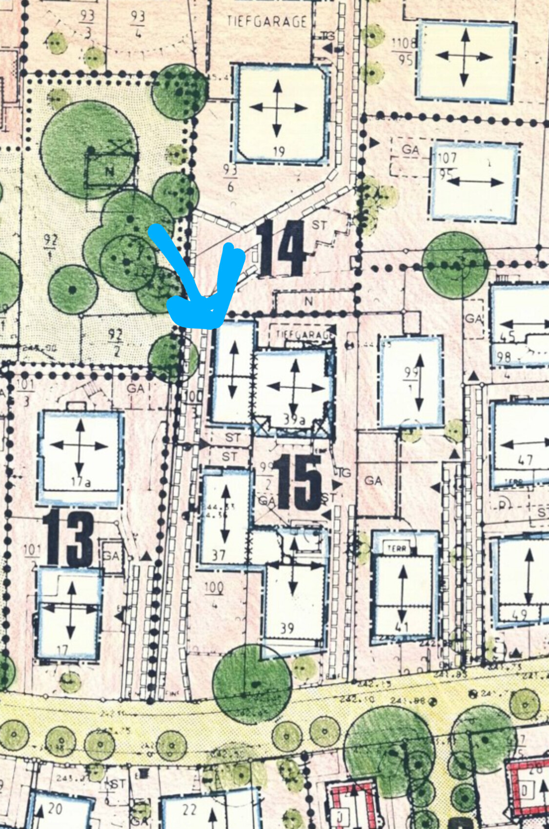 Stadtplan-Schnappschuss: Gebäude 13–15, Straßen, grüne Bäume; blauer Pfeil markiert eine Straßenecke.