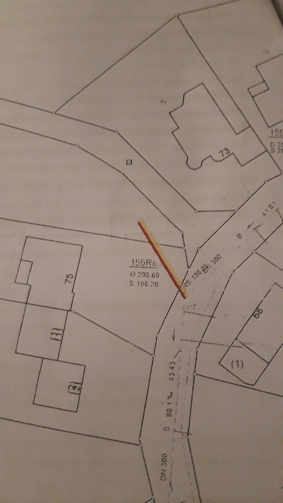Lageplan eines Grundstücks mit Gebäuden, Straßenverlauf und gelb-roter Markierungslinie.