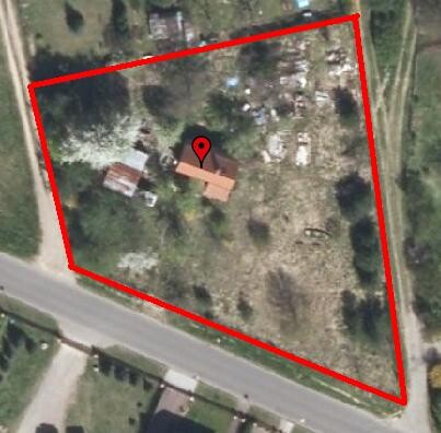 Luftbild eines dreieckigen Grundstücks mit roter Umrandung und einem Haus in der Mitte
