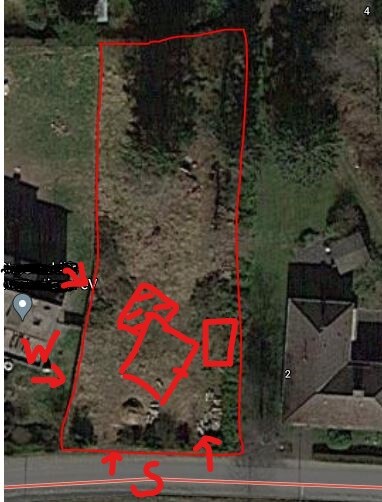 Luftbild eines Grundstücks mit roter Umrandung, Bäumen, Gebäuden und Straße unten.